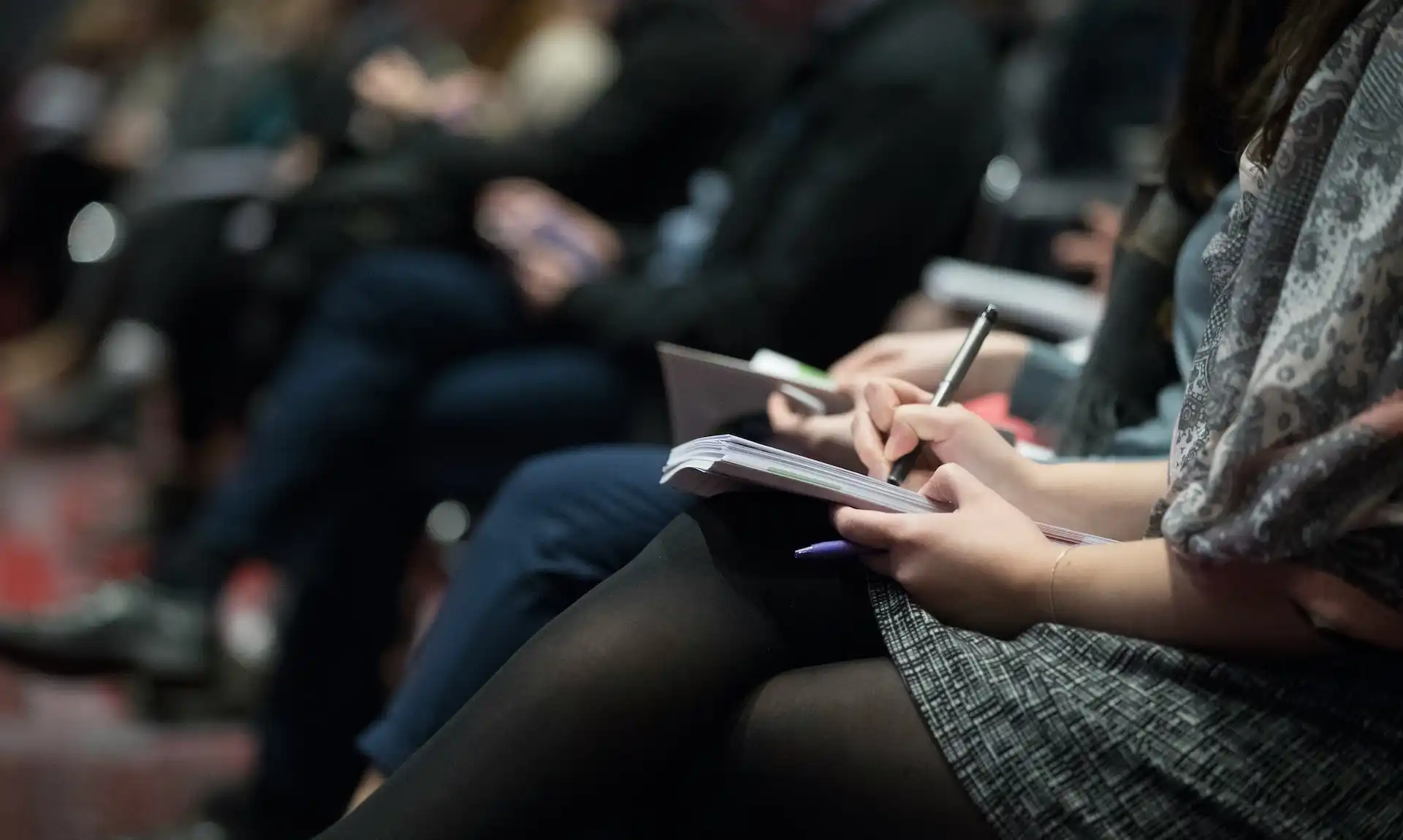 Someone note-taking at a press conference, representing our media training services